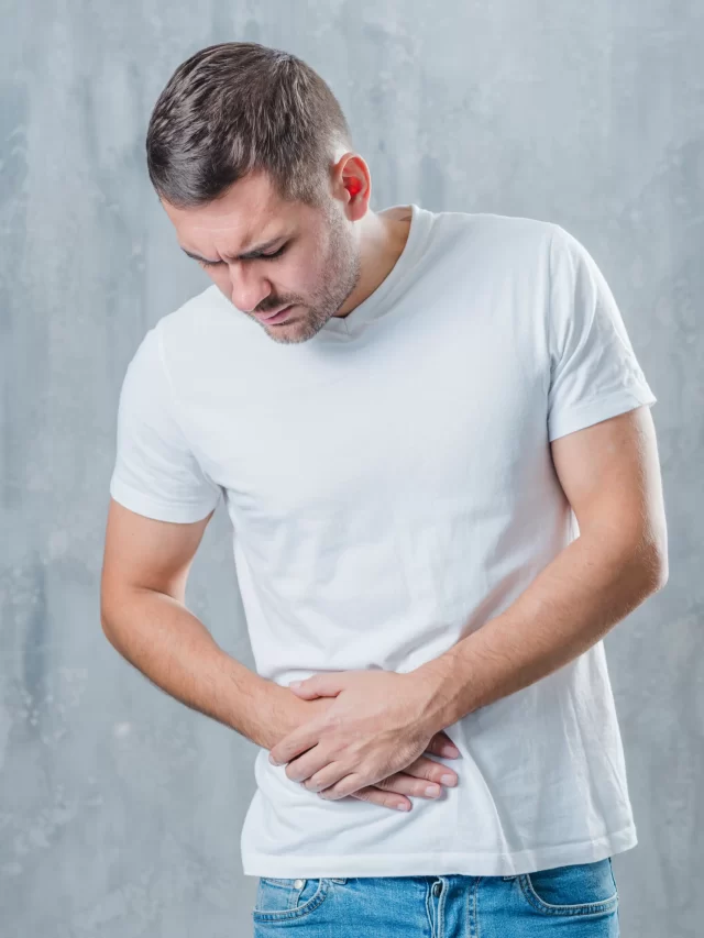 man-standing-against-gray-background-suffering-from-abdominal-pain